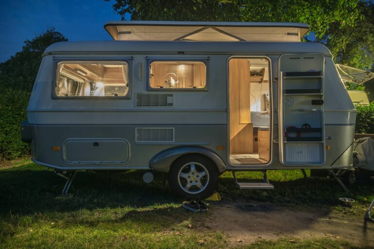 A classic caravan or motorhome with the lights on in the evening.