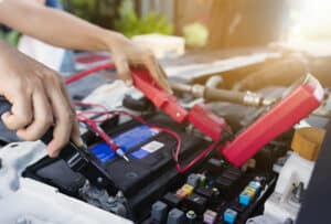 Close up of auto mechanic jumping battery car.