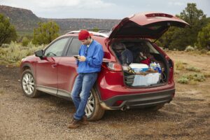 Man using smartphone beside car, Zion, Utah, USA